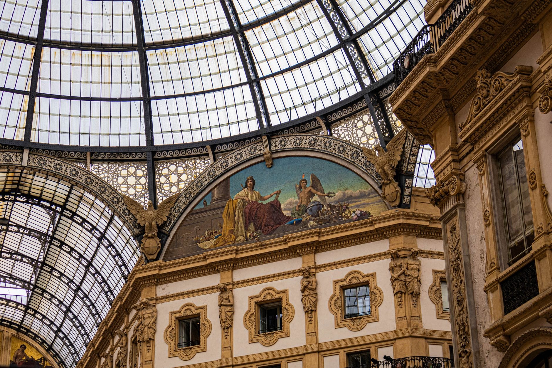 The ornate glass dome and painted arch inside the Galleria Vittorio Emanuele II shopping arcade, Milan