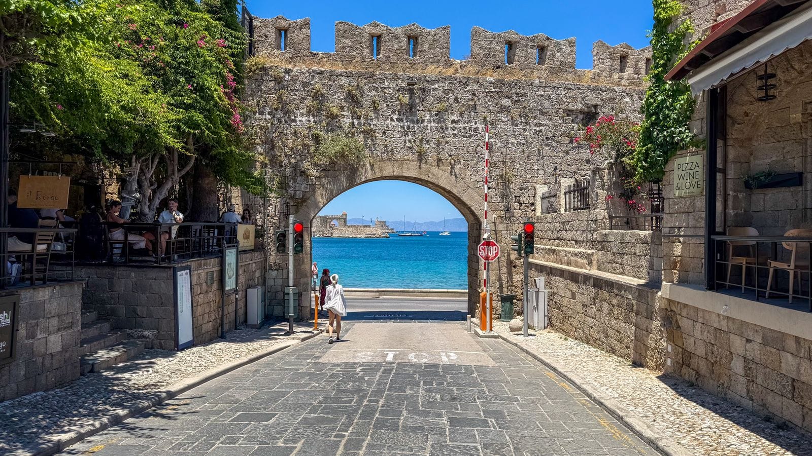 A stone gate in the walls of Rhodes Old Town framing the bright blue sea beyond