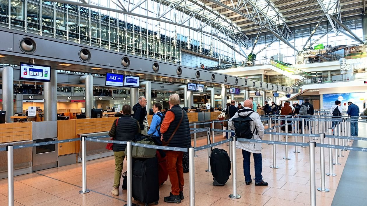 Travellers queuing at an airport check-in counter, the situation Ryanair's £55 airport check-in fee is designed to make rare