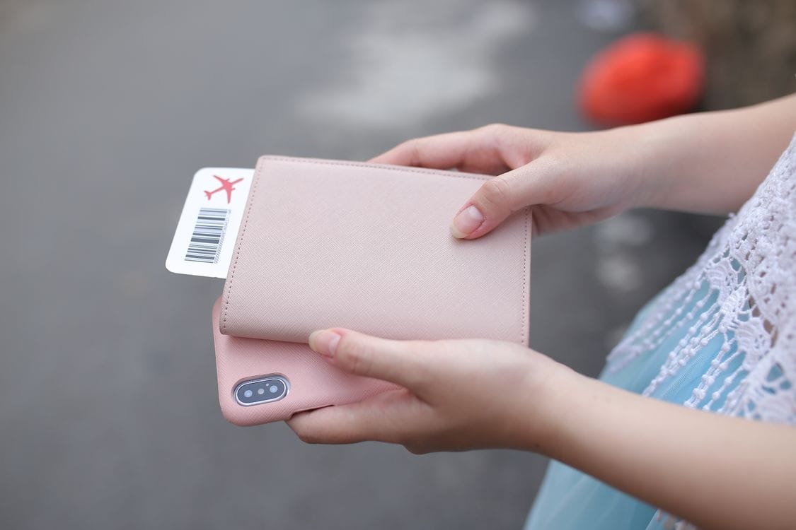 A boarding pass tucked into a phone case held in someone's hands
