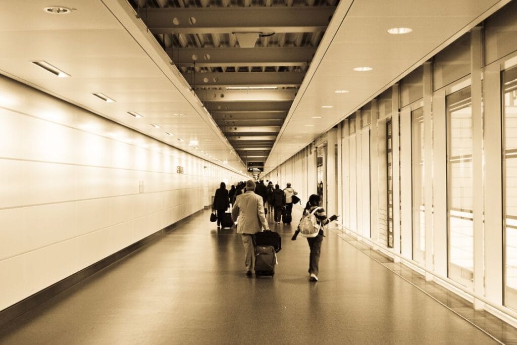 Ryanair missed flight: travellers pulling wheeled suitcases along a brightly lit airport terminal corridor
