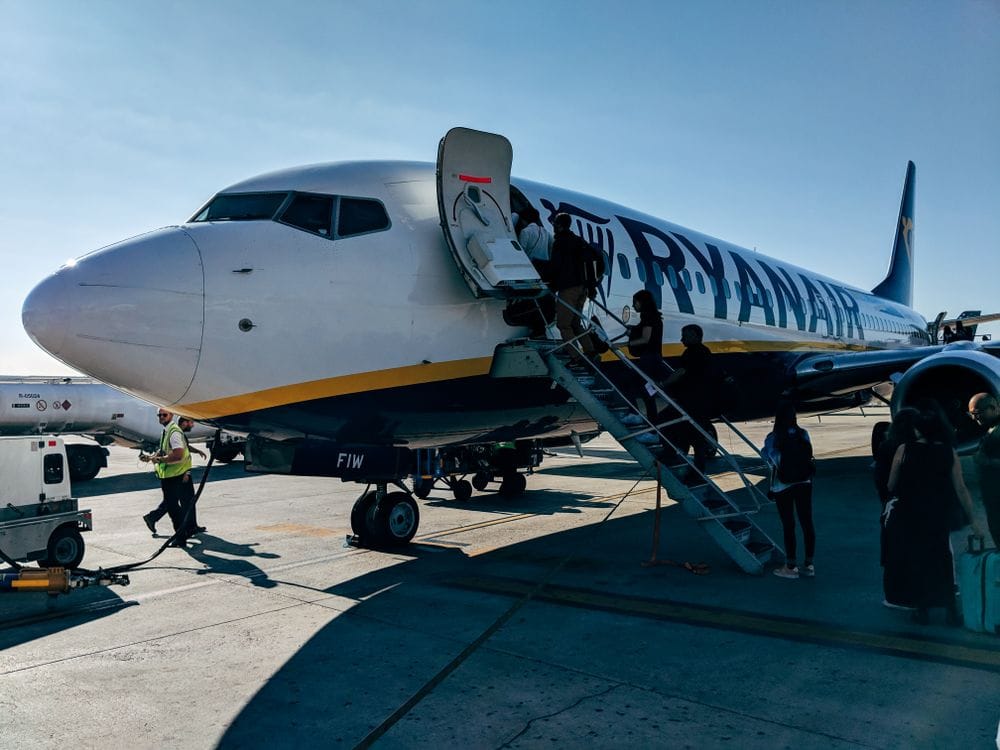 Passengers boarding a Ryanair Boeing 737 up the aircraft steps carrying cabin bags
