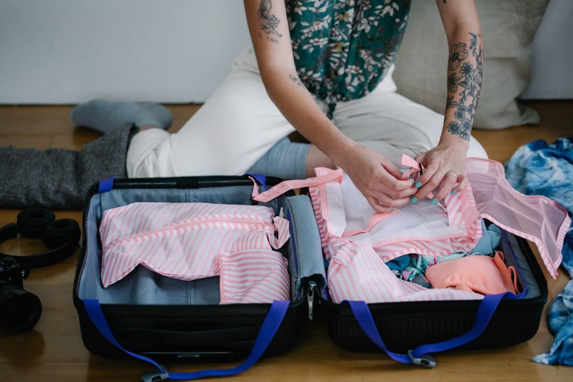 A woman packing a suitcase on the floor at home, checking items against airline rules before a trip