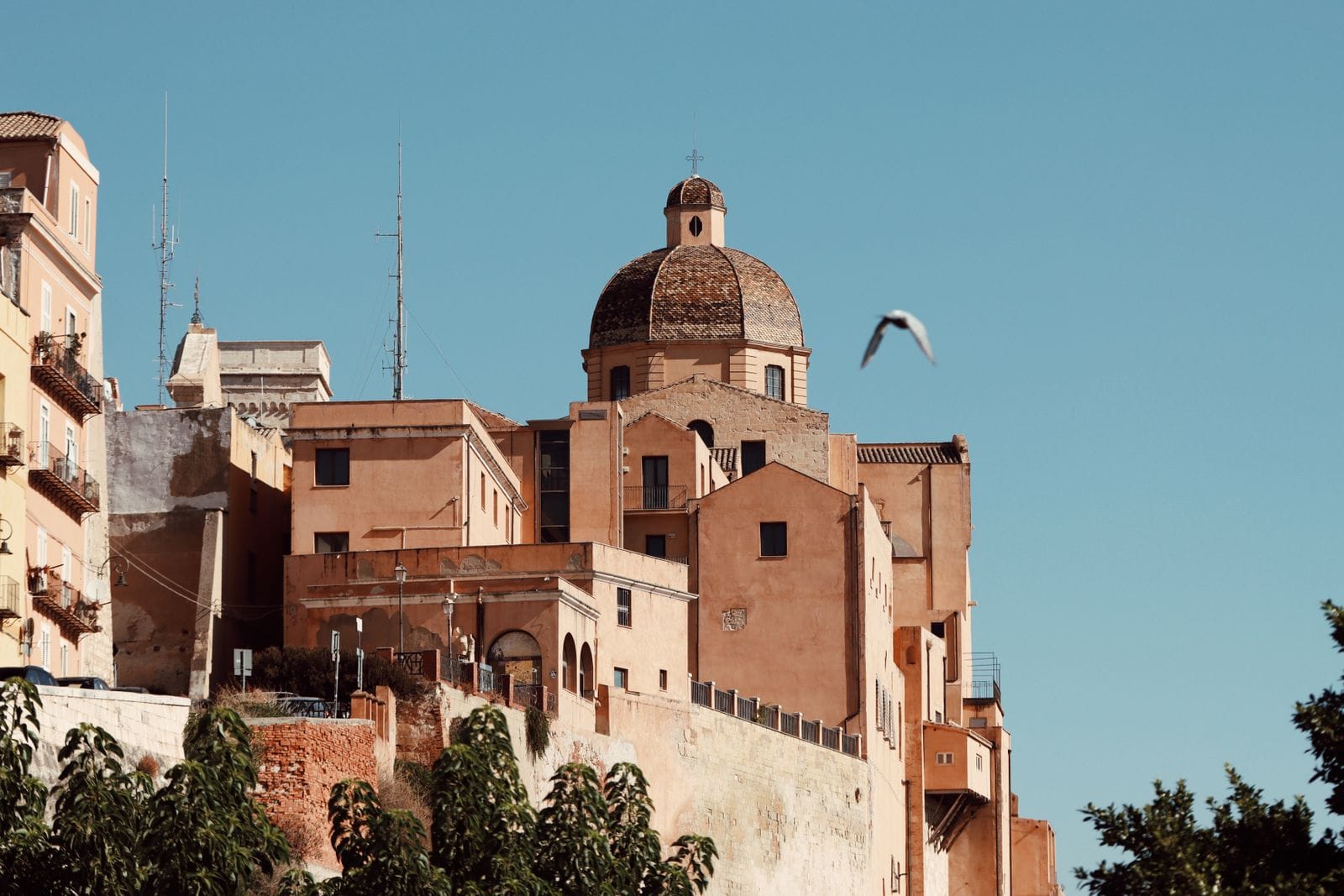 The tiled dome of Cagliari cathedral rising above the ochre buildings and bastion walls of the Castello quarter