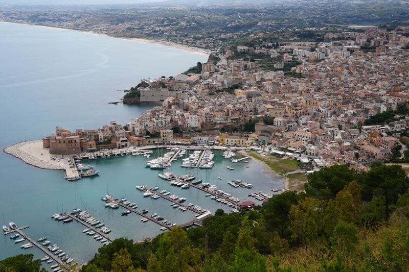 Aerial view of Castellammare del Golfo's marina and old town on Sicily's northwest coast, boats moored in turquoise water