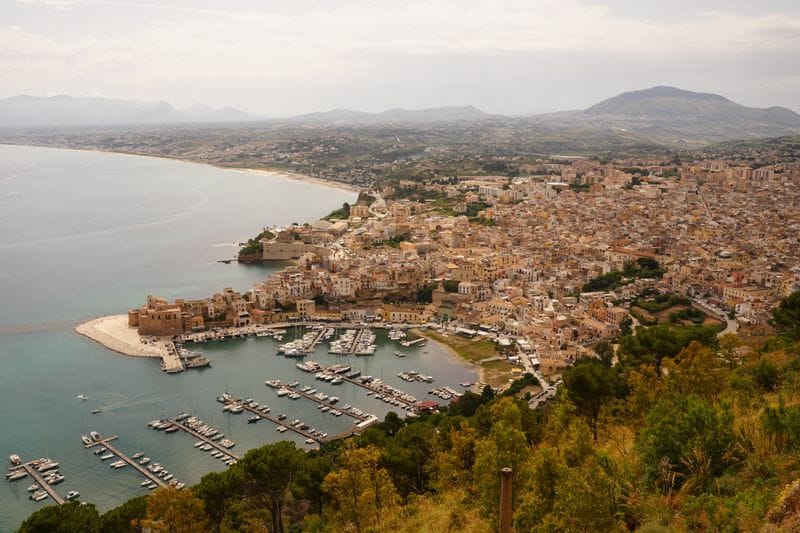 Boats moored in Castellammare del Golfo's marina on Sicily's northwest coast, hillside town behind