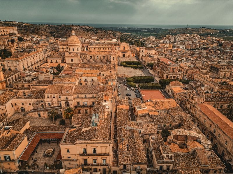 Aerial view of Noto's baroque old town in Sicily, with the sea visible in the distance