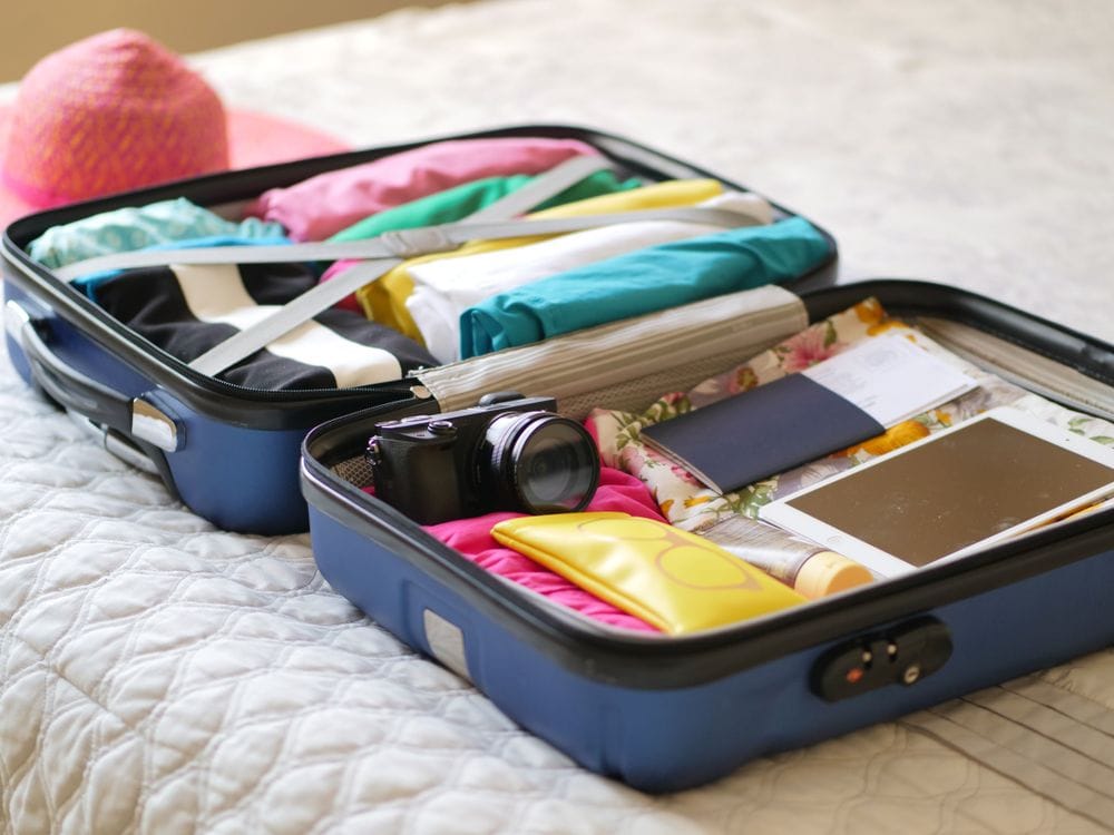 Open suitcase packed for a trip with a passport and camera visible, the paperwork a travel insurance claim would need