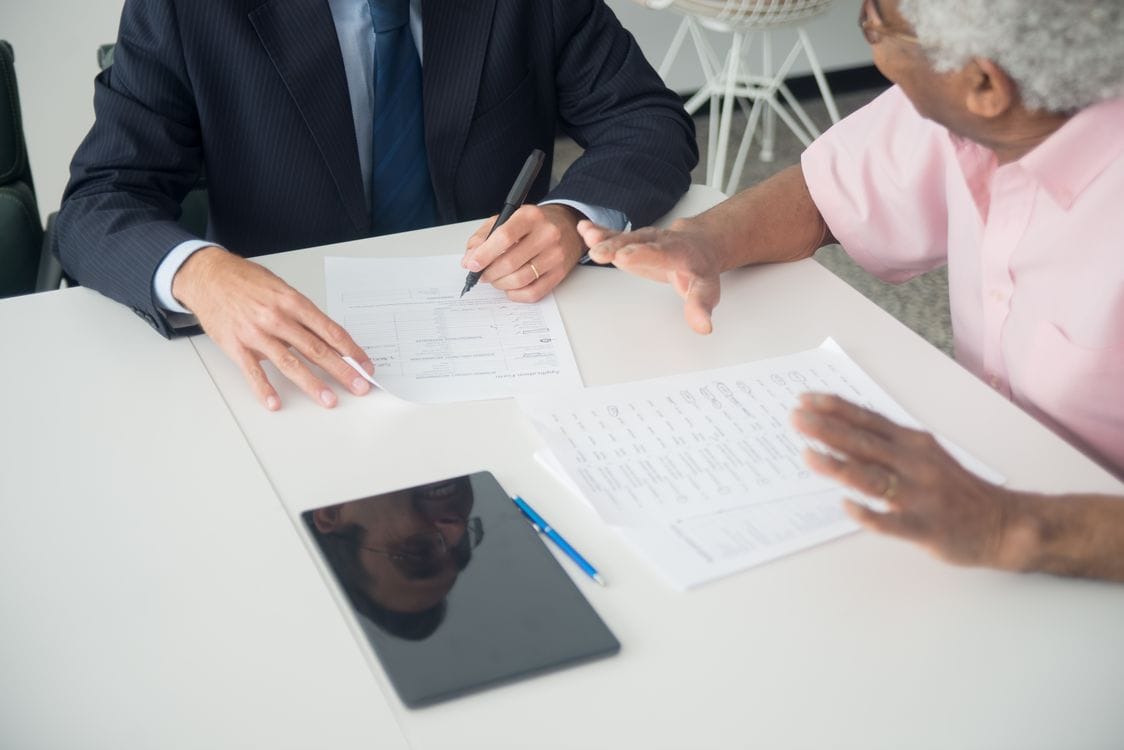 An older client going through a policy document with an advisor, the kind of one-to-one conversation worth having before choosing between Staysure and Avanti