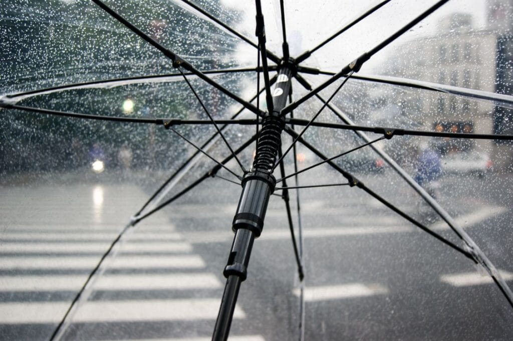 Looking up through a clear umbrella at a rainy street, a genuine cover metaphor for travel insurance protection
