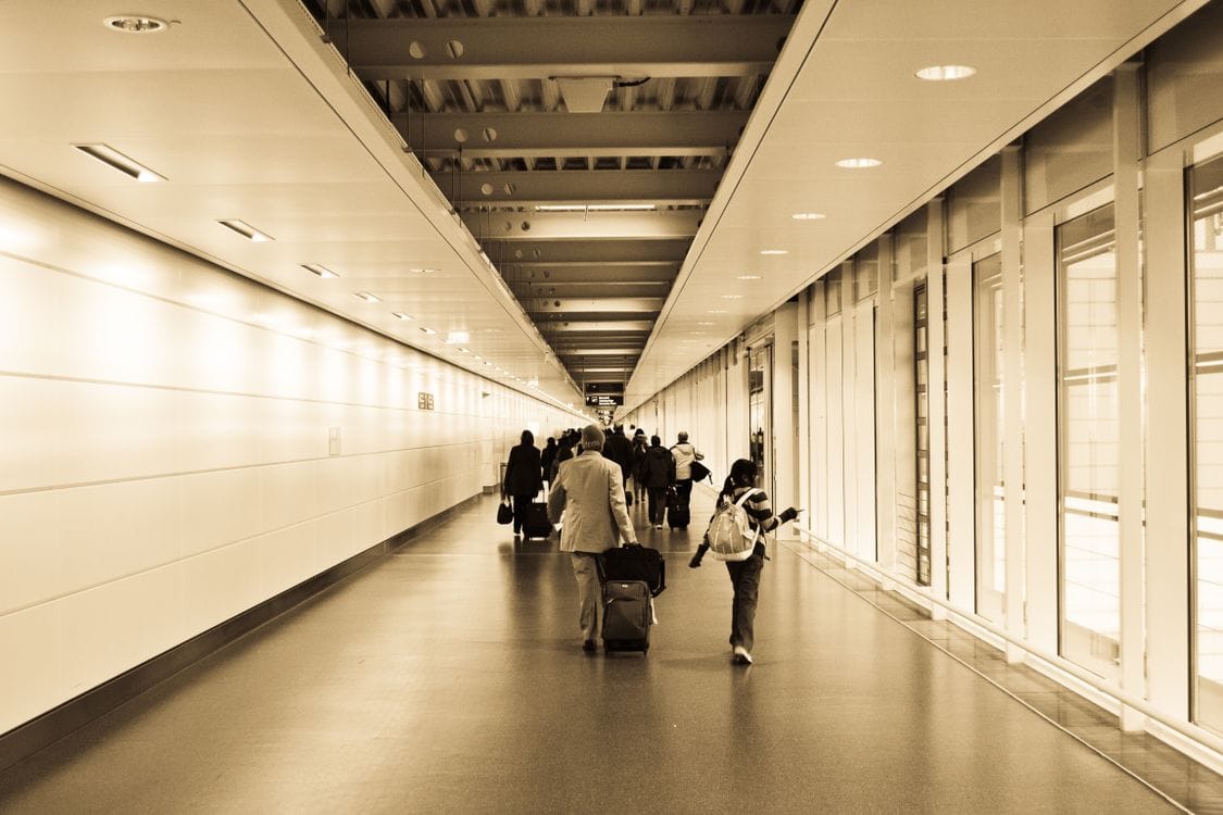 Travellers walking through an airport corridor, weighing up whether to fix a TUI name error or start a fresh booking