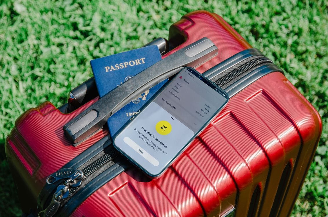 A passport and smartphone resting on a packed suitcase, ready for a trip