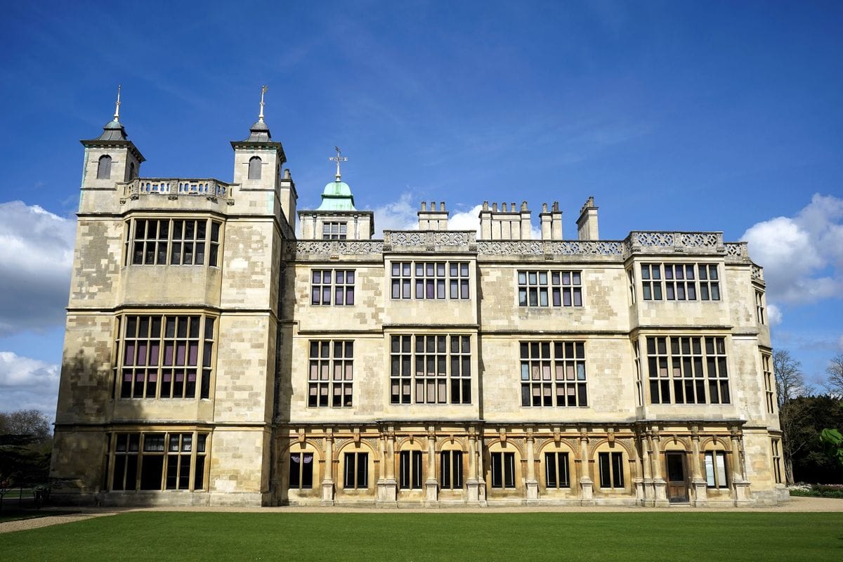 A grand English manor house with turrets and formal lawns, similar in style to Warner's country estate hotels