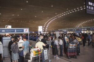 When does Wizz Air check in open: a busy airport check-in hall with passengers at self-service kiosks and desks