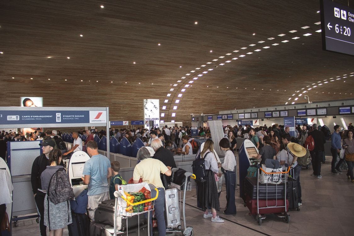 When does Wizz Air check in open: a busy airport check-in hall with passengers at self-service kiosks and desks