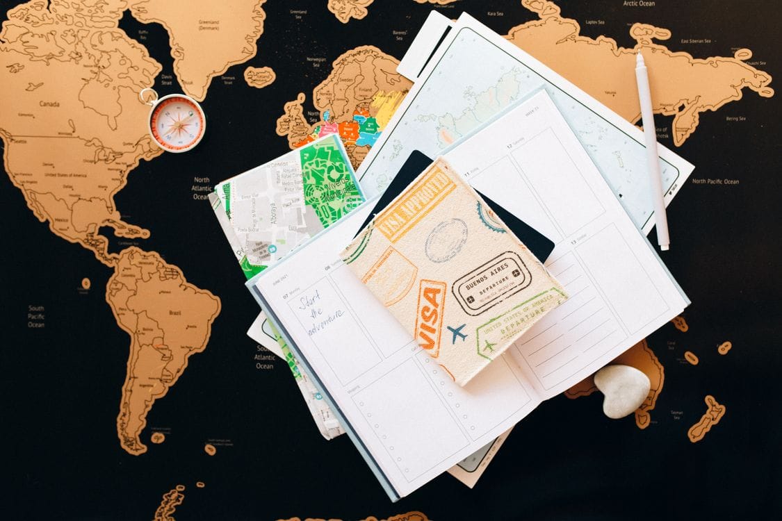 A passport, planner and world map laid out for travel planning