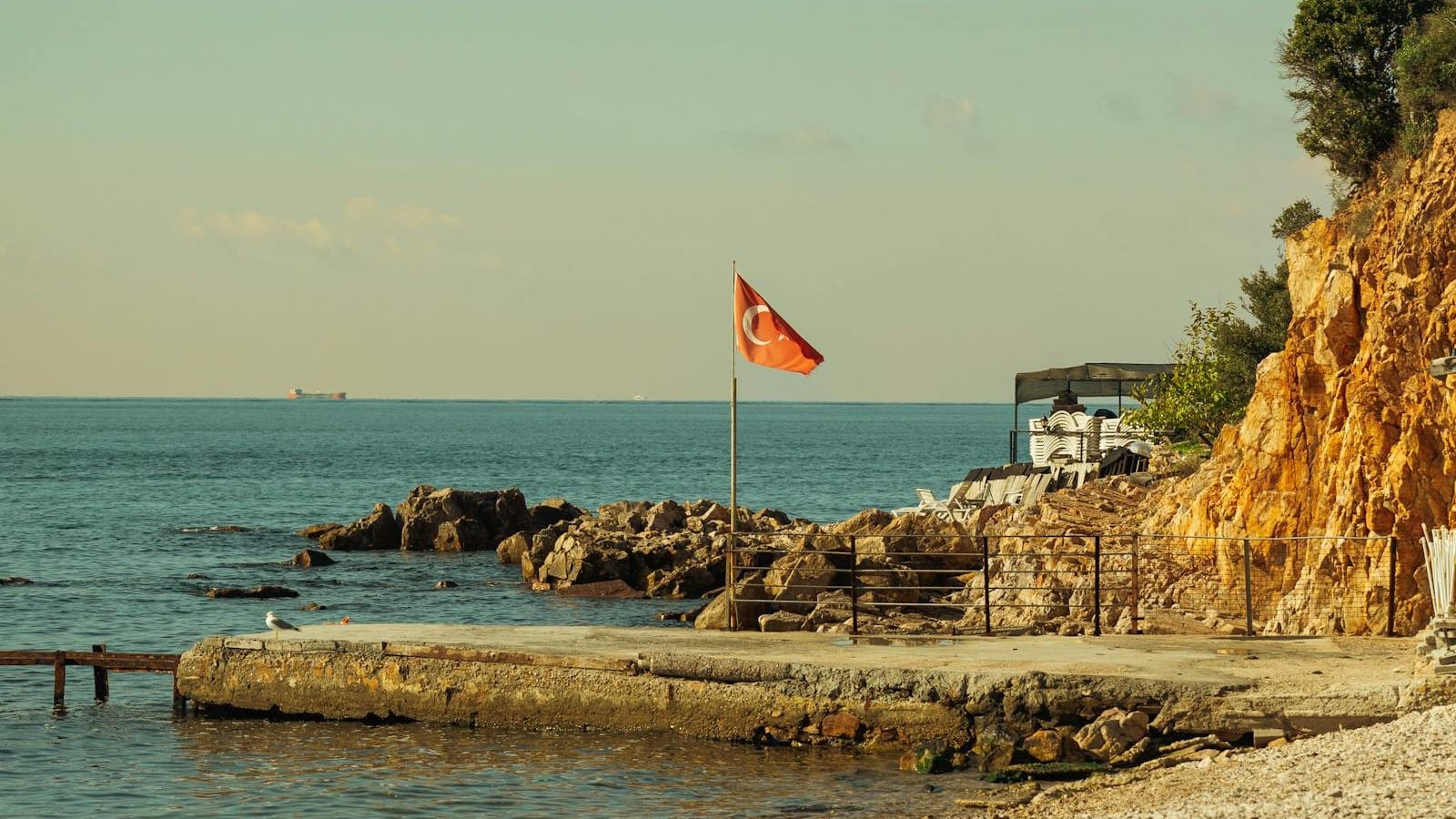 Rocky Turkey coast with a Turkish flag beside the sea, used for a Wowcher Izmir holiday deal