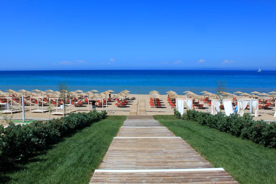 Sunloungers and umbrellas in rows on a Zakynthos beach with clear blue water