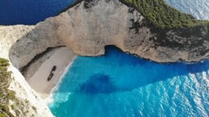 Aerial view of Navagio Shipwreck Beach on Zakynthos, a rusting wreck on white sand ringed by limestone cliffs and turquoise sea