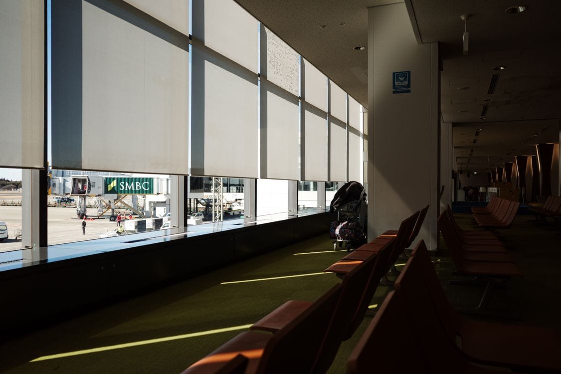 Empty rows of seats by the window of an airport departure lounge in low afternoon sun