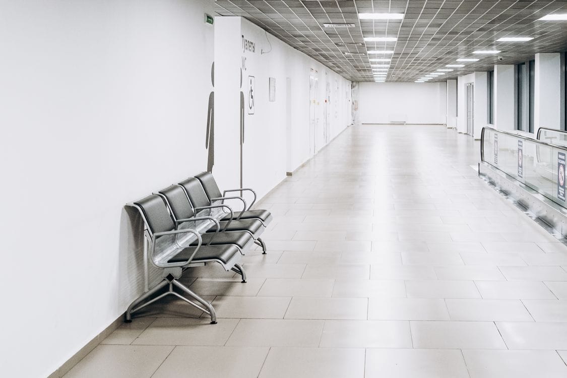 An empty, brightly lit airport corridor with a row of metal seats