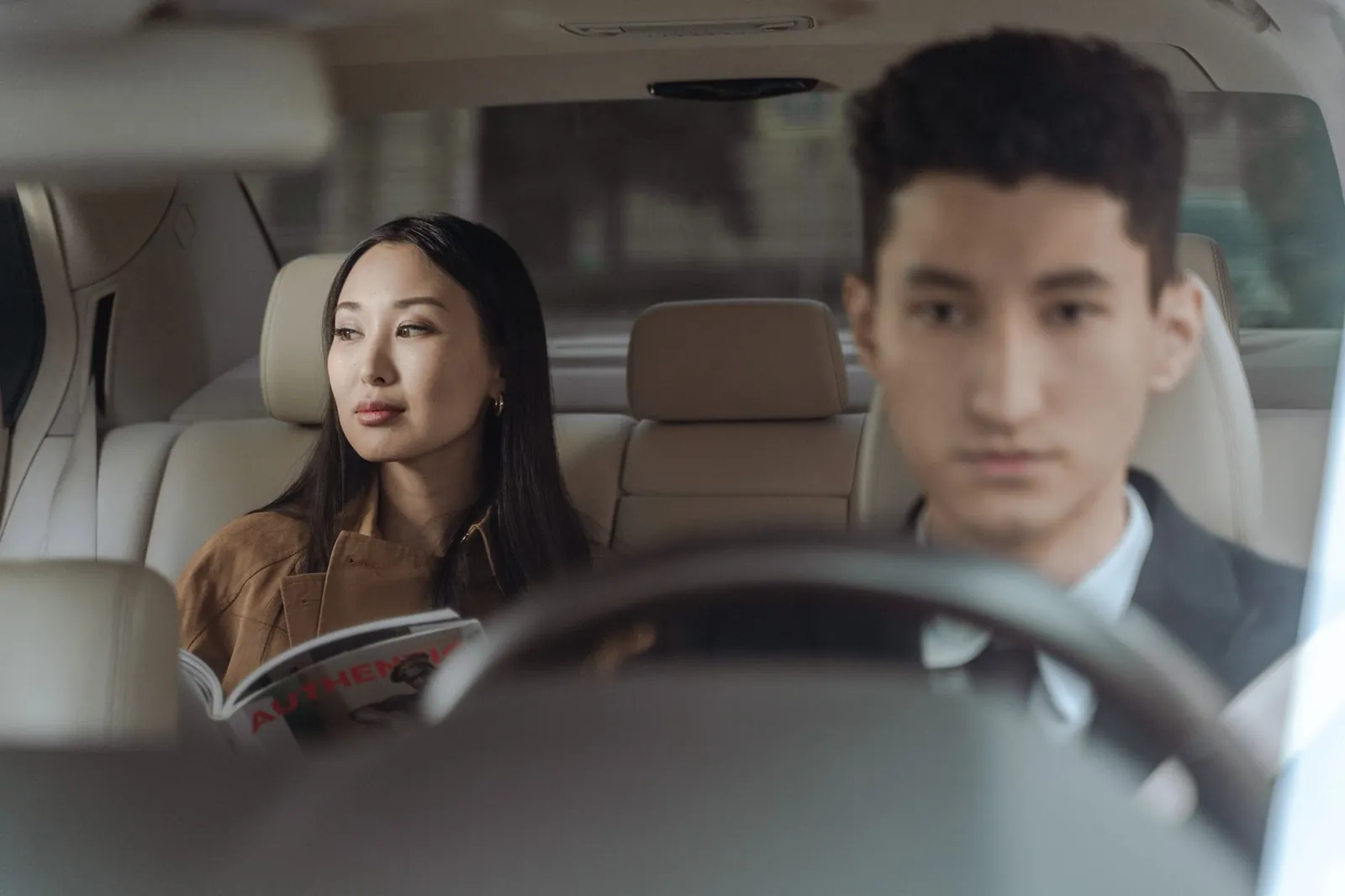 A passenger sitting in the back of a private airport transfer car, driver at the wheel