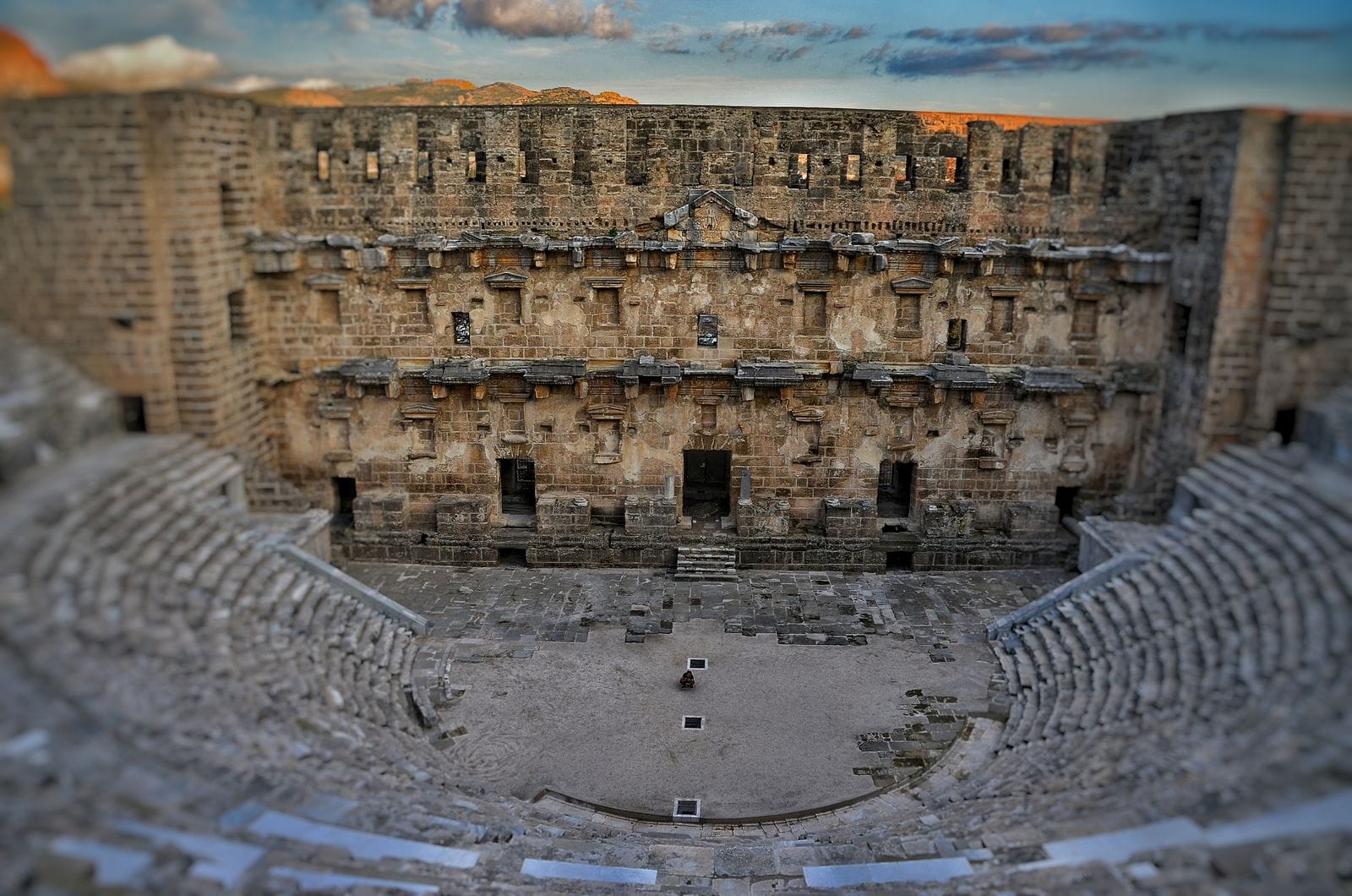 The well-preserved stage building of the Aspendos Roman theatre near Antalya, tiered stone seating in the foreground