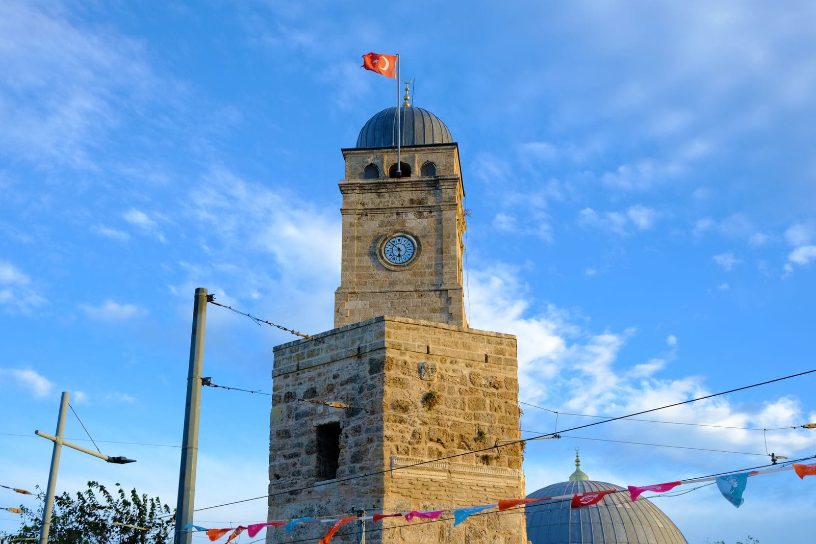 The stone Saat Kulesi clock tower marking the entrance to Kaleici, Antalya's old town, under a clear blue sky