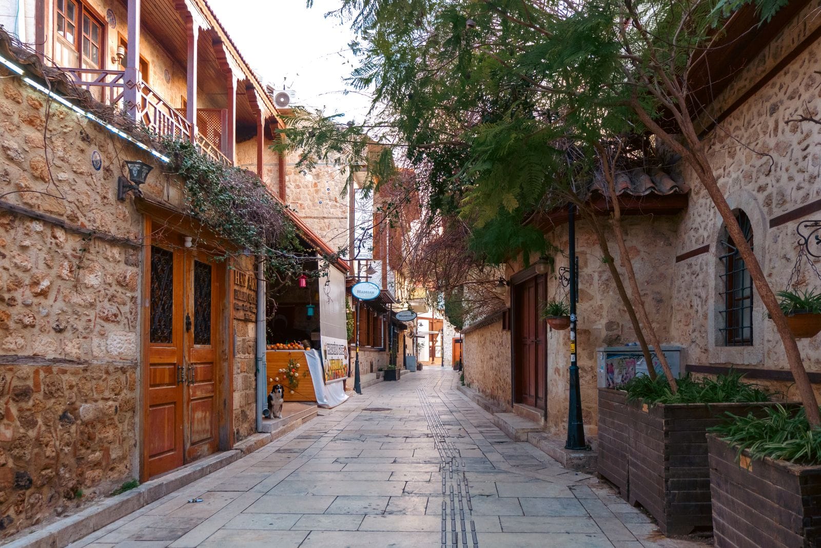 A narrow cobbled street in Kaleici, Antalya's old town, lined with restored Ottoman-era stone houses and wooden shutters