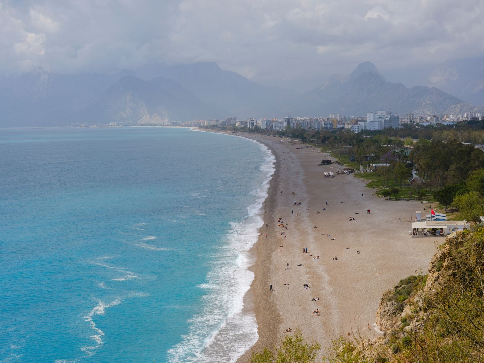 Aerial view of Konyaalti Beach in Antalya, a long pebble beach curving beneath the Taurus Mountains