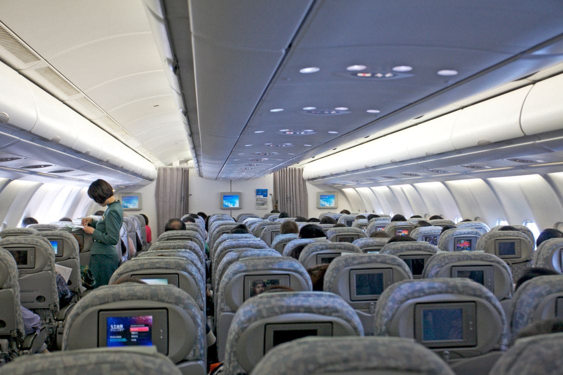 Passengers seated inside an airplane cabin, seen from behind