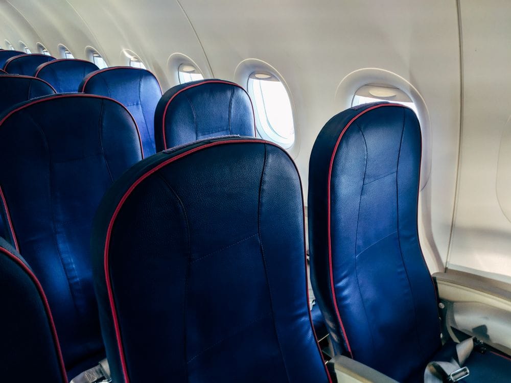 Empty airline seats beside a row of windows on an airplane