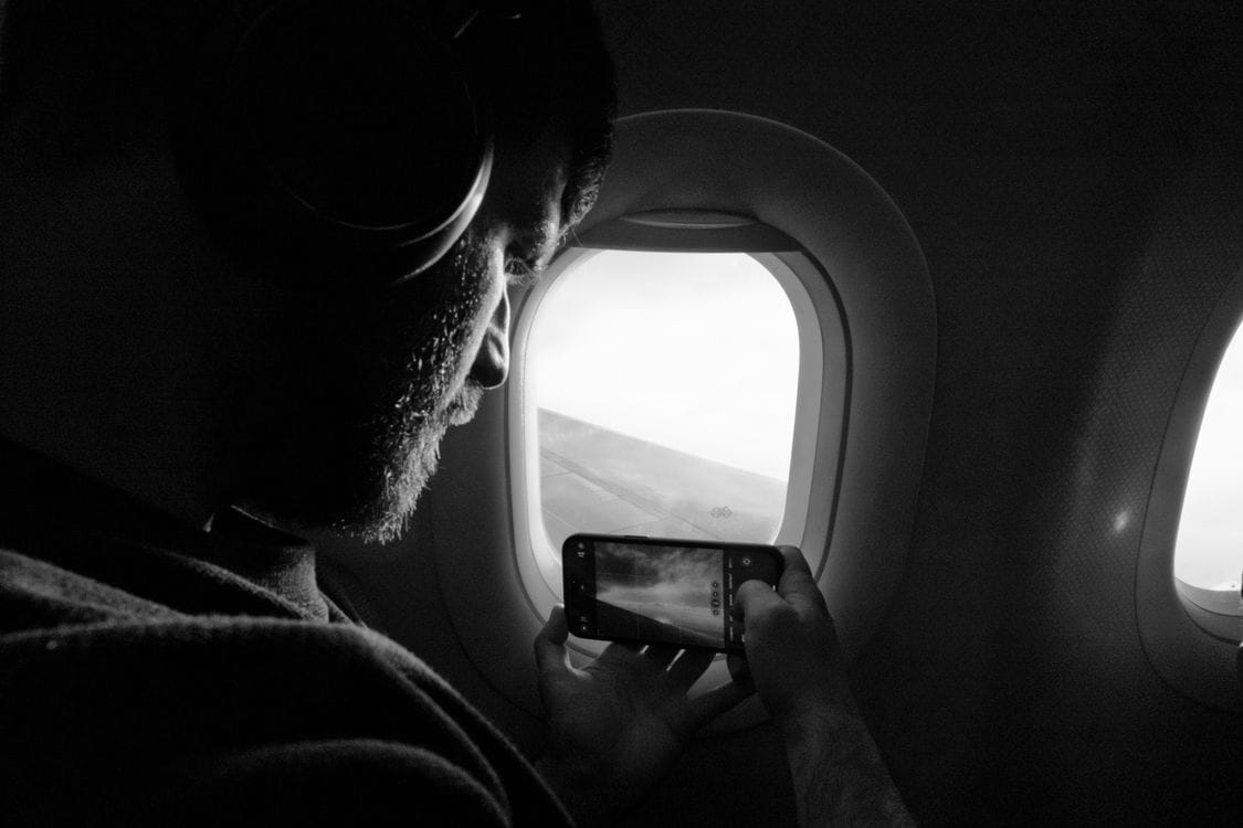 Silhouette of a passenger using a phone beside an airplane window