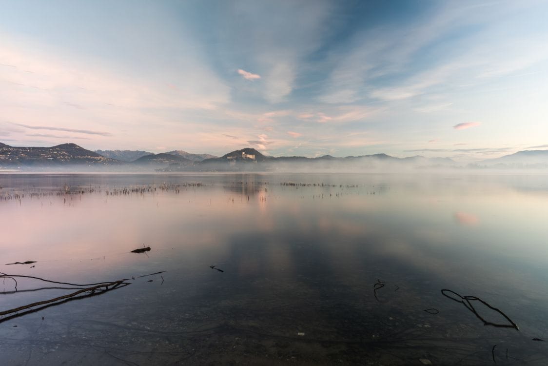 A misty lake at sunrise with a mountain reflection