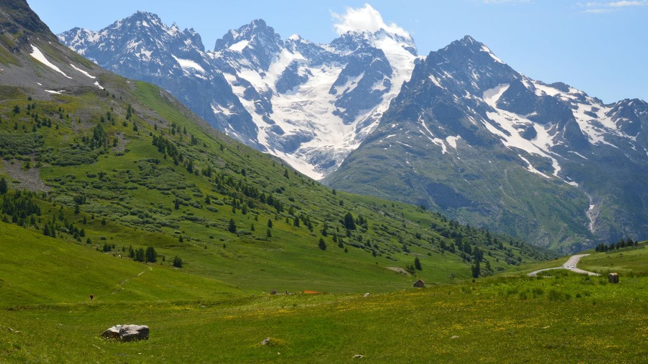 A green alpine valley beneath snow-capped mountains