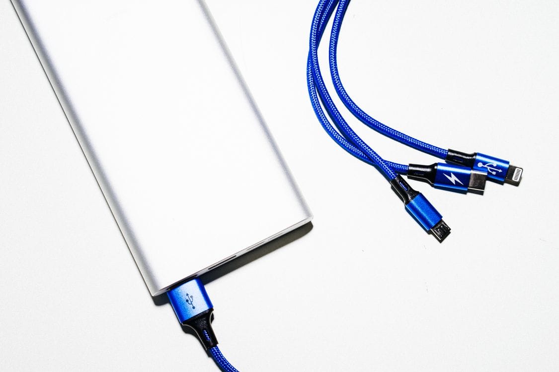 A silver power bank with blue braided charging cables on a white background