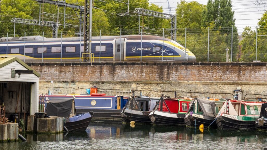 A Eurostar train passing narrowboats moored on a London canal