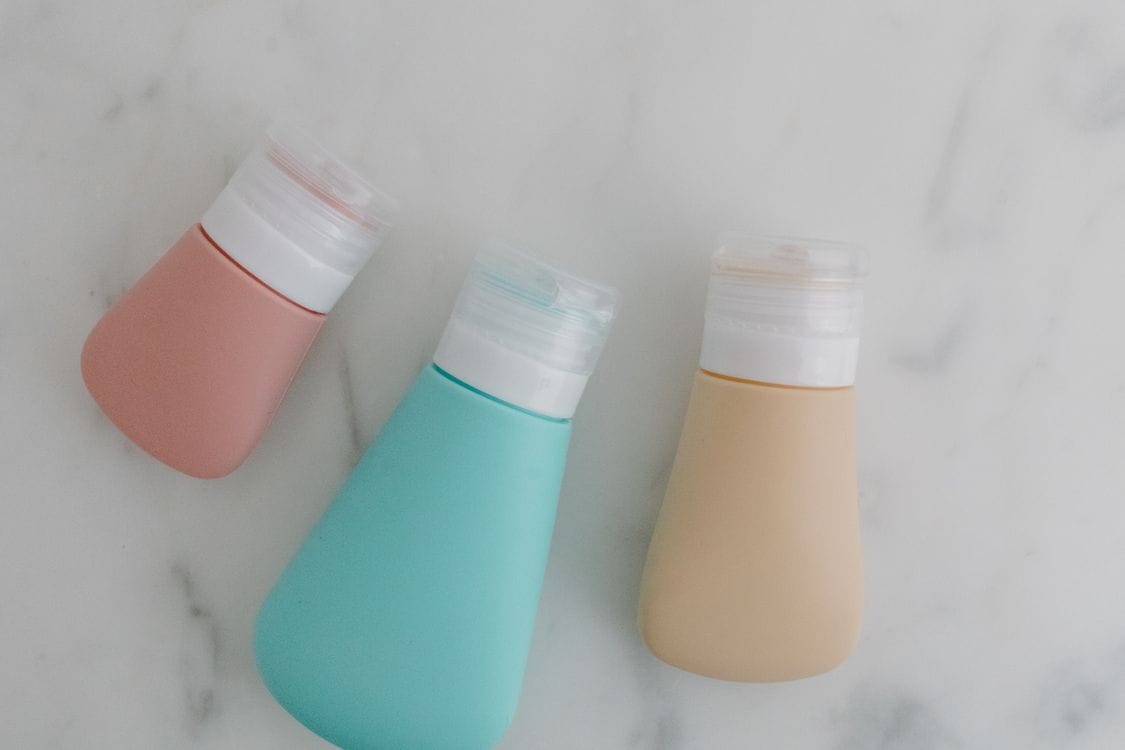 Jet2 liquid rules: three silicone travel bottles in pink, teal and beige on a marble surface
