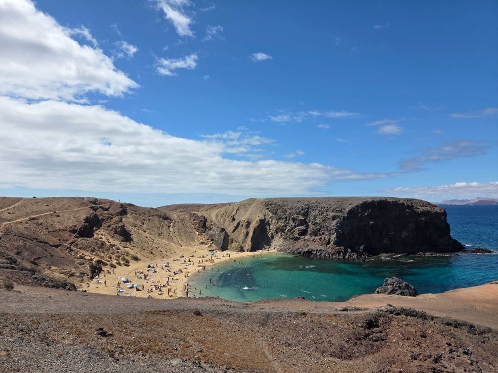 Papagayo beach in Lanzarote, a small sandy cove below brown volcanic cliffs