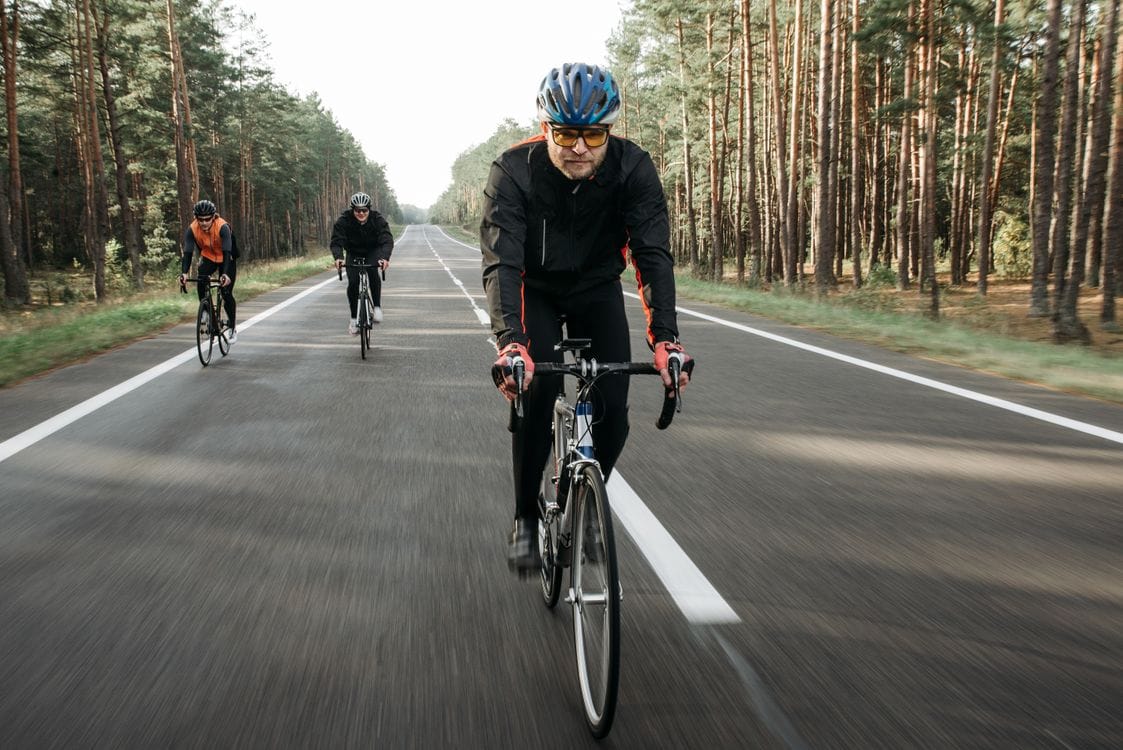 A group of cyclists riding together on a forest road