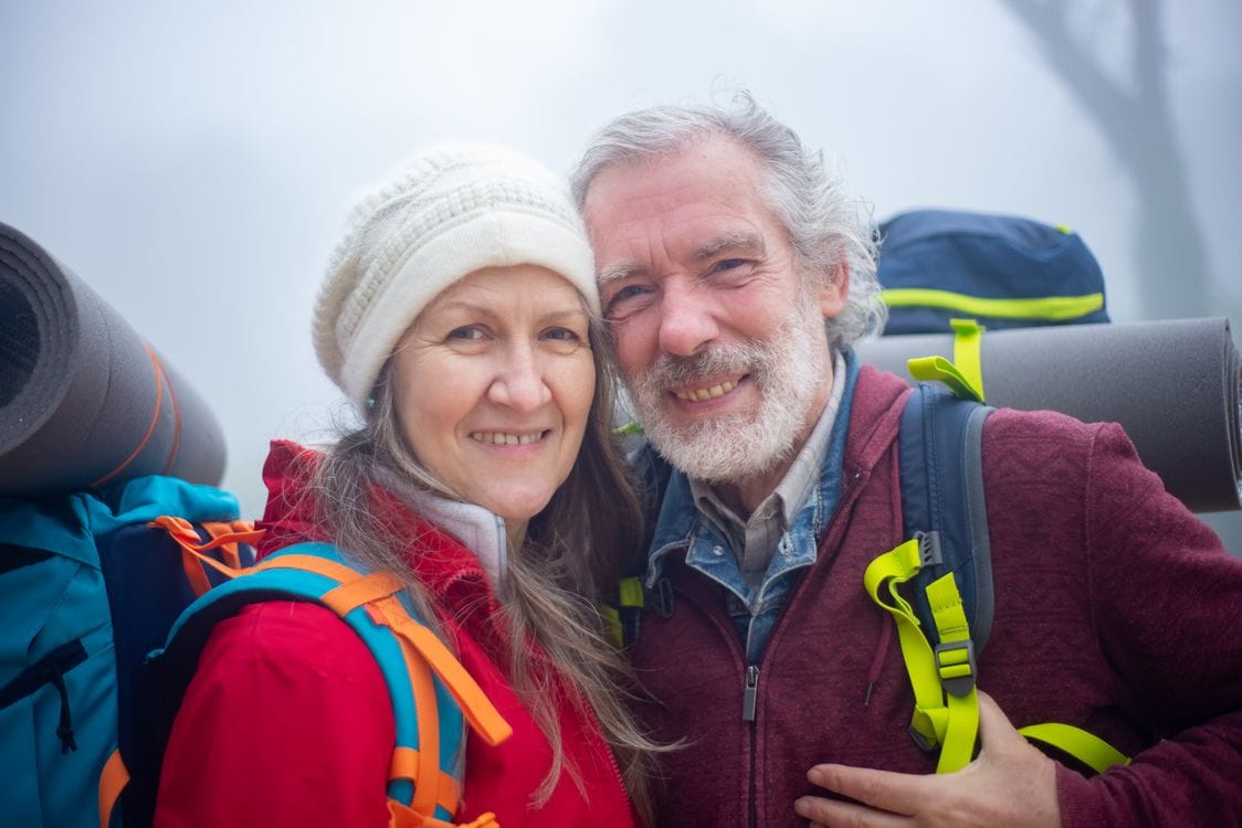 Just Travel Cover reviews: an elderly couple hiking together in misty mountains, reflecting the no upper age limit this broker offers across the UK and Europe