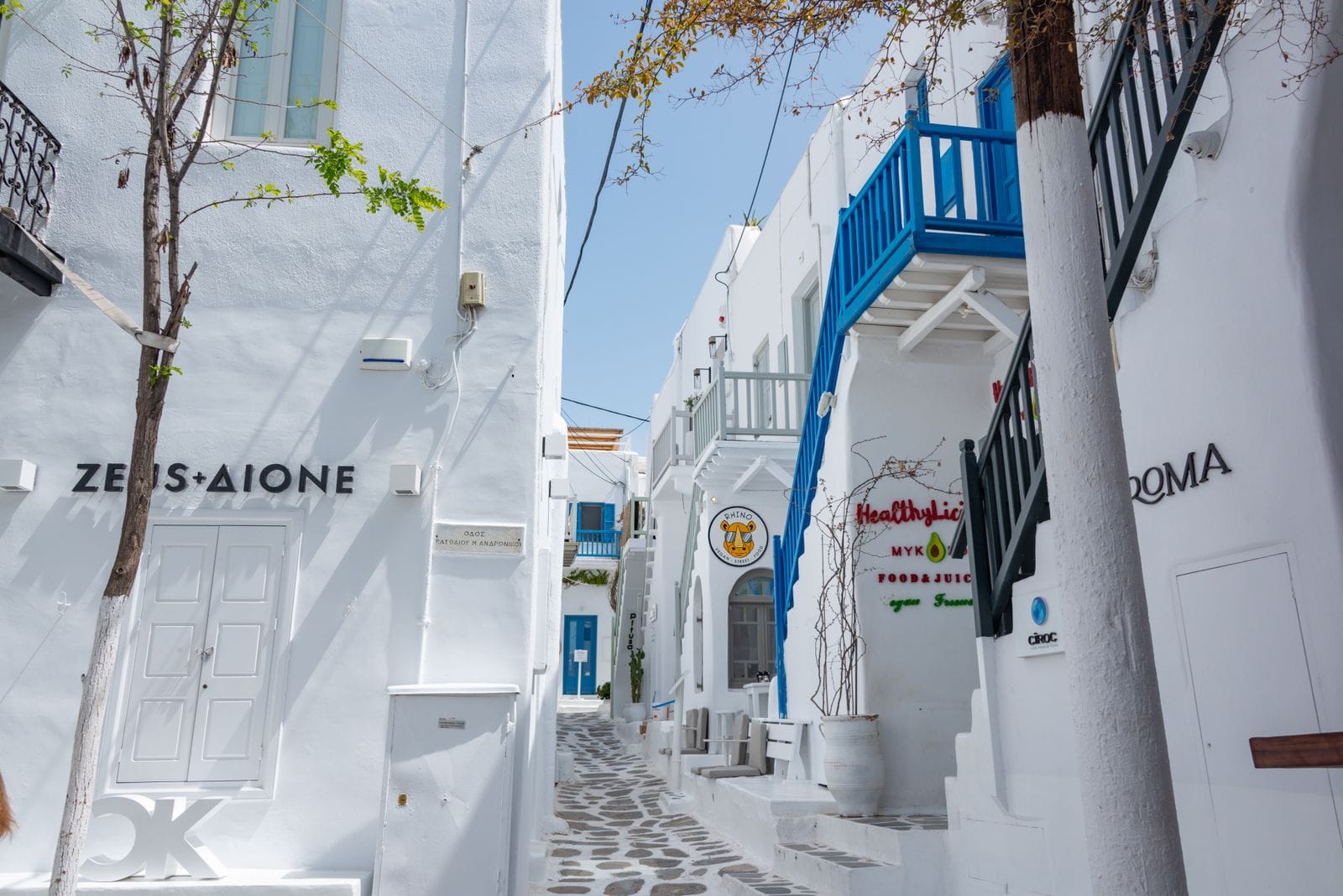 A narrow whitewashed alley in Mykonos Town lined with shops and a blue-railed staircase