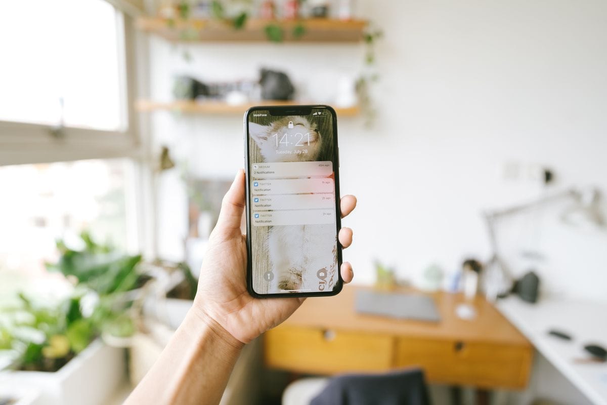 A hand holding a smartphone showing a list of notifications on the lock screen