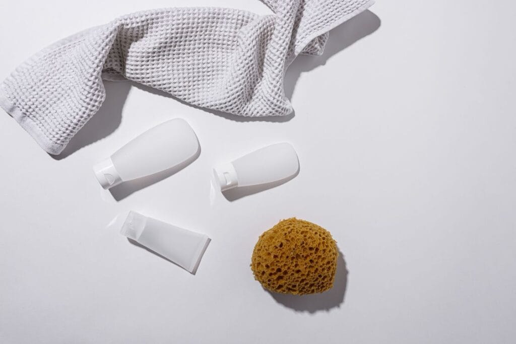TUI liquid rules: three white travel-size tubes and bottles beside a natural sponge and a waffle towel