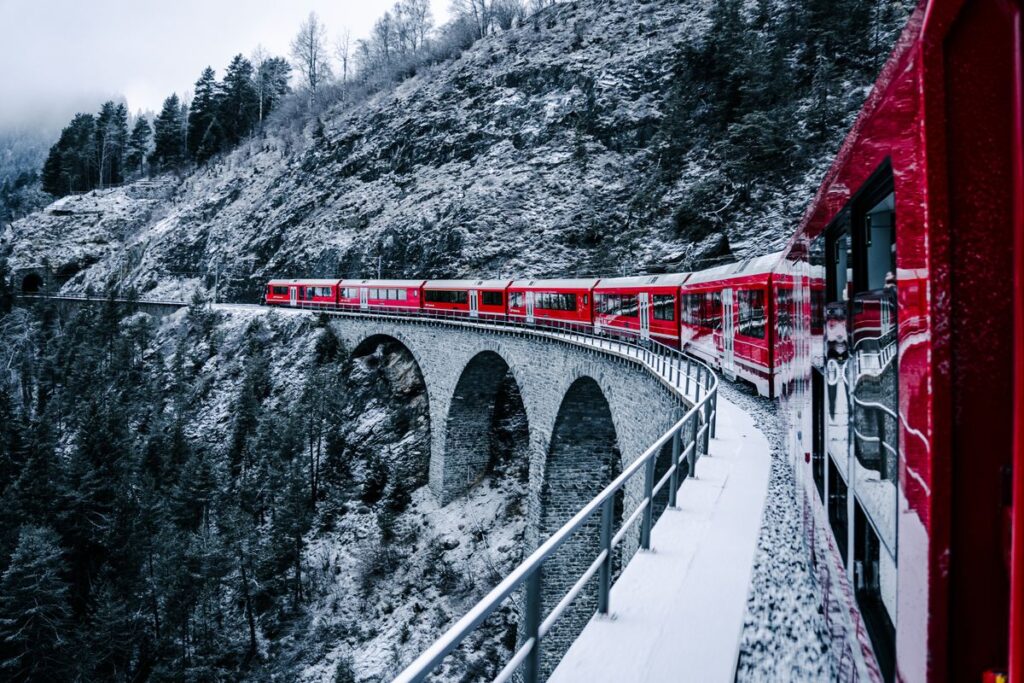 Red mountain train crossing a snow-covered stone viaduct in the Swiss Alps for our Bernina Express deal