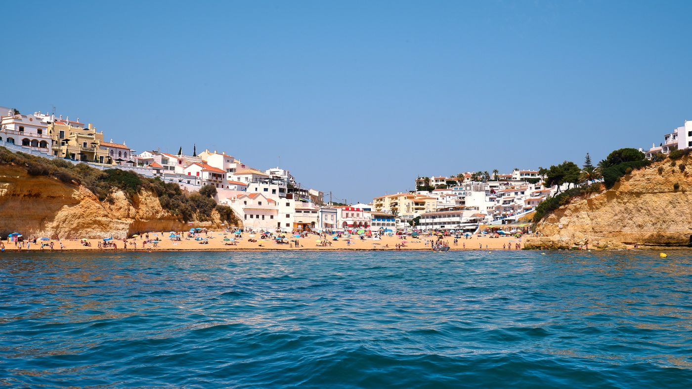Carvoeiro village and its sandy beach below Algarve cliffs, seen from the sea