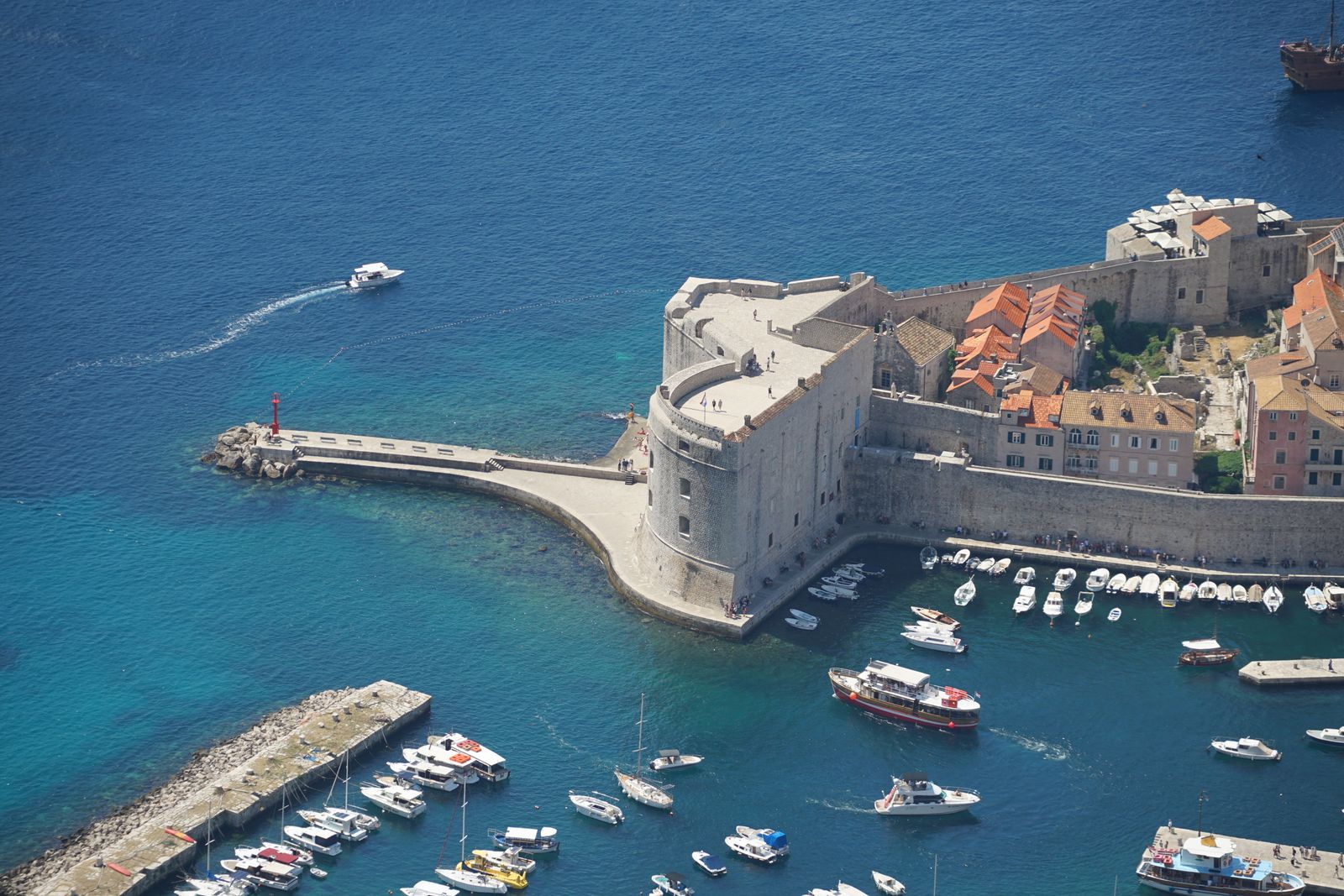 Aerial view of the Old Port in Dubrovnik with St John's Fort, a breakwater and boats on bright blue water