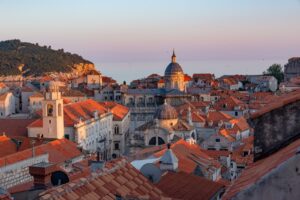 Is Dubrovnik expensive: terracotta rooftops and church domes of Dubrovnik Old Town glowing at sunset above the Adriatic