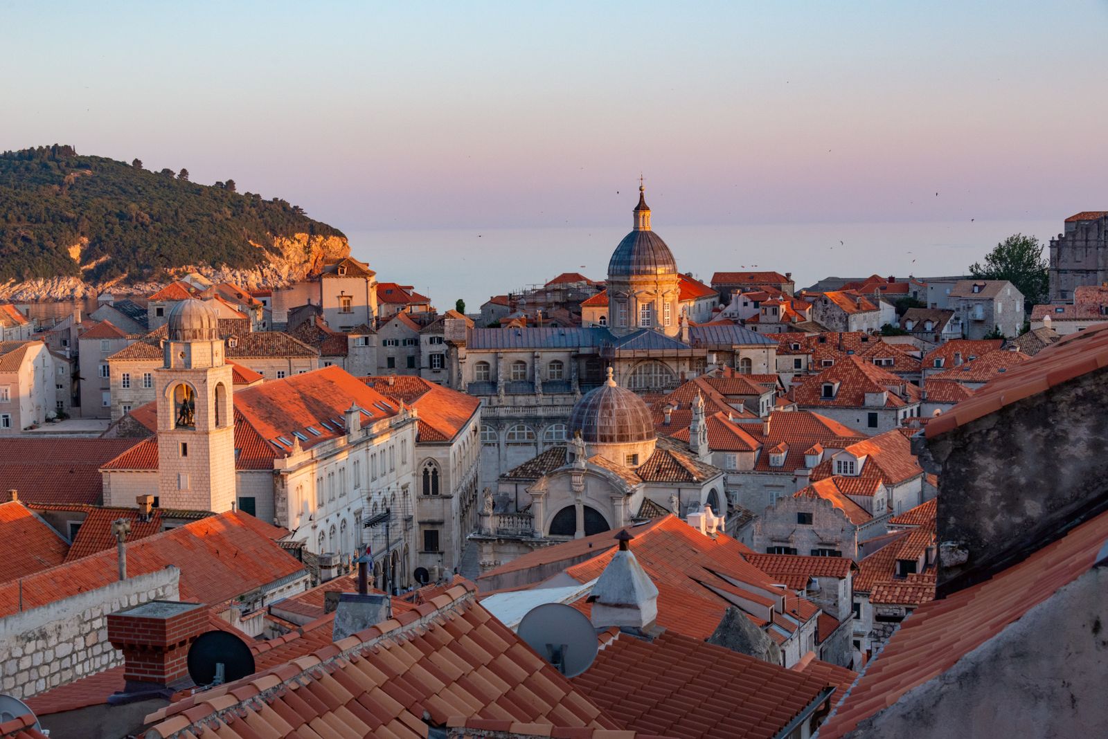 Is Dubrovnik expensive: terracotta rooftops and church domes of Dubrovnik Old Town glowing at sunset above the Adriatic