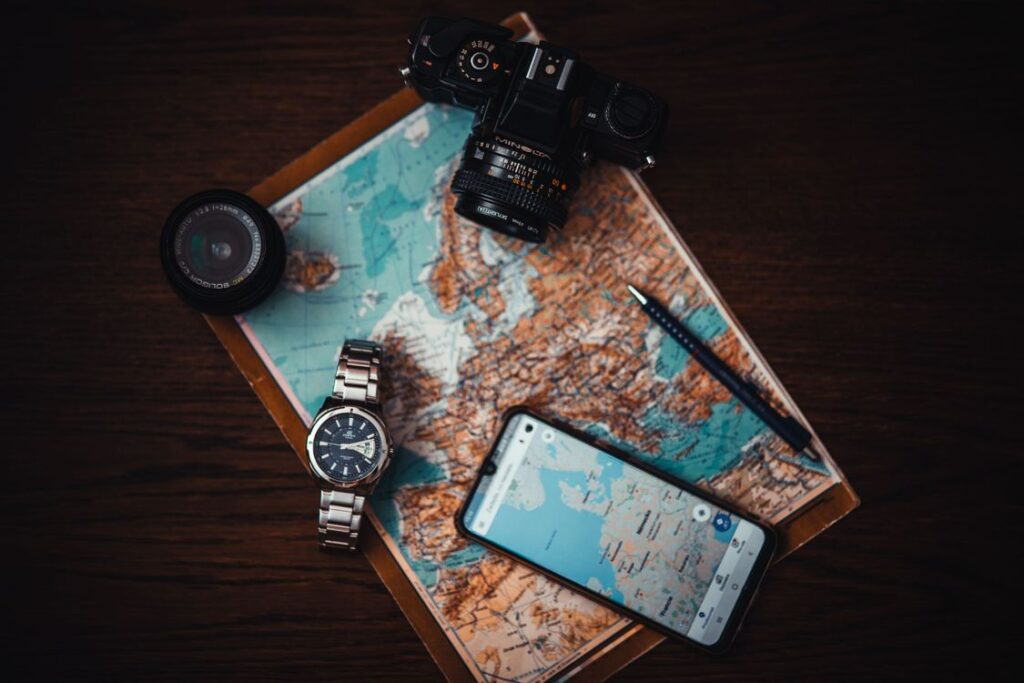 A flat lay of a Europe map with a phone, camera, watch and pen, the kit behind our esim reviews for European trips